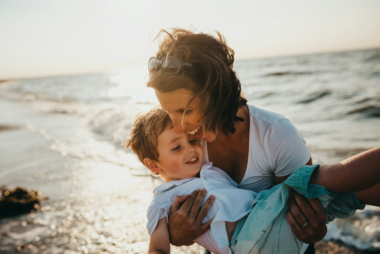 A caregiver hugging a laughing little boy in warm golden light