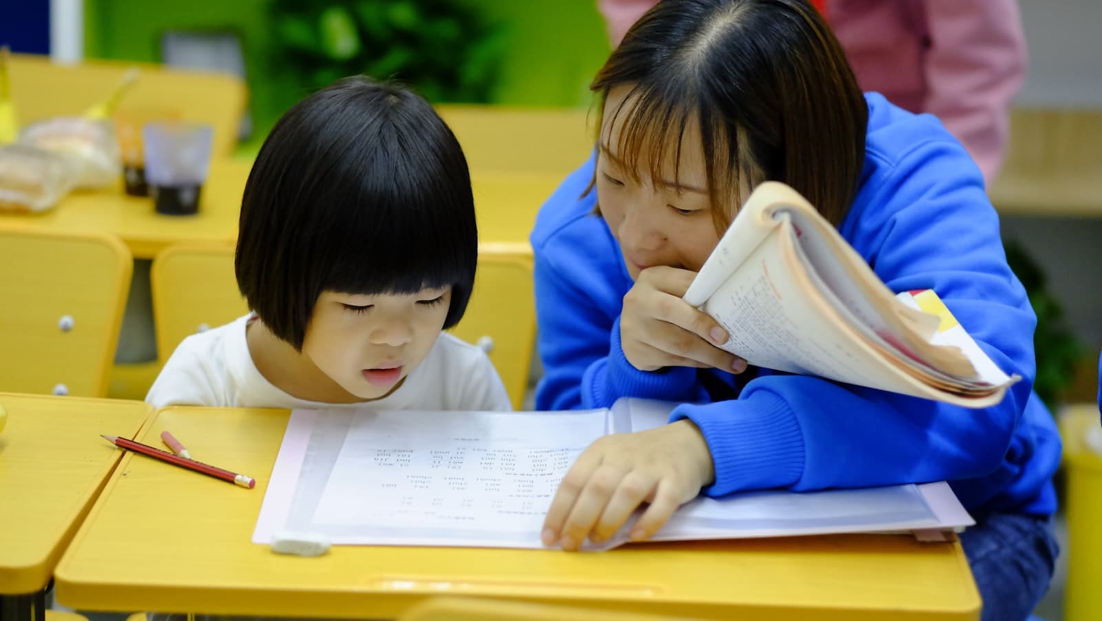 A tutor helping a young girl with her homework